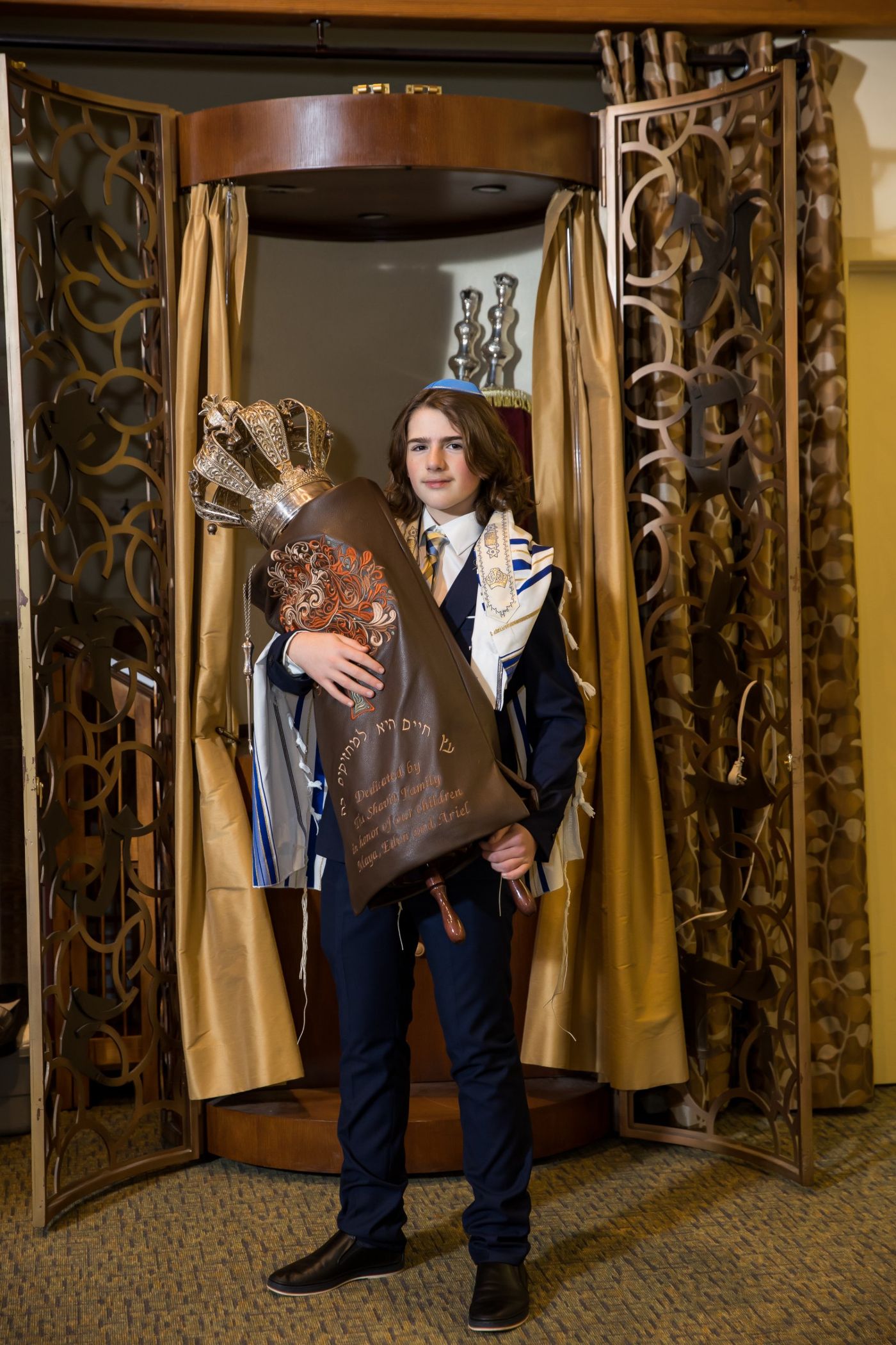 Bar Mitzvah boy holding the Torah in front of the ark